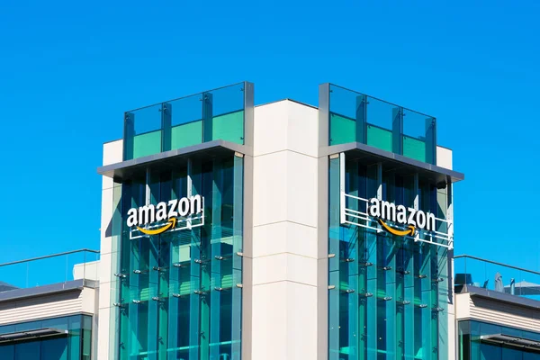 Logo firmy Amazon z podpisanym pomarańczowym uśmiechem na szklanej fasadzie kampusu firmy w Dolinie Krzemowej — Zdjęcie stockowe