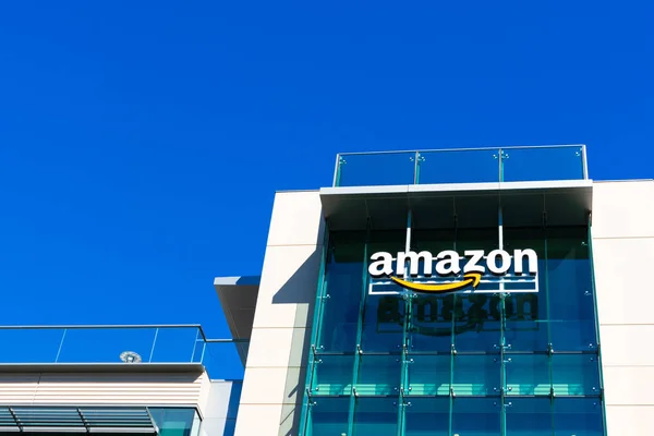 Логотип Amazon с характерной оранжевой улыбкой на стеклянном фасаде кампуса компании в Кремниевой долине — стоковое фото