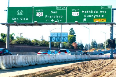 Otoyol geliştirme projesi devam ediyor. İşçi, yaya ve trafik güvenliği için bariyer. 237 ve 101 numaralı otoyol işaretleri altında araç trafiği