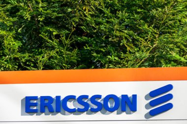 Ericsson imzası Silikon Vadisi kampüsündeki ağ ve telekomünikasyon şirketinin arkasında yeşil ağaçlar var.