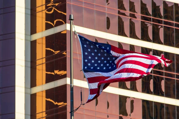 Een vlag van Usa. Amerikaanse vlag. De vlag van de Verenigde Staten wappert prachtig in de harde wind. Achtergrond glazen gevel van modern kantoorgebouw — Stockfoto