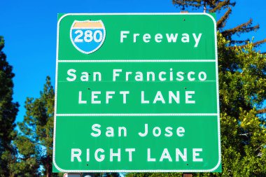 280 numaralı otoyol tabelası sürücülere güneşli Silikon Vadisi 'ndeki San Francisco ve San Jose' ye giden yolu gösteriyor. Yeşil ağaçlar ve mavi gökyüzü arka planı.