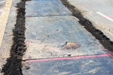 Çelik plakalar açık kazıyı geçici olarak kapatıyor ve araç ve yaya trafiğine olanak sağlıyor. Çelik plakaların kenarlarını tüylendirmek için kullanılan soğuk asfalt karışımı ile geçici asfalt döşeme.