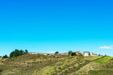 Yeşil tepenin üzerine inşa edilen yerleşim alanının manzarası. Gözlerden uzak yerlerde kentsel yaşam evleri.