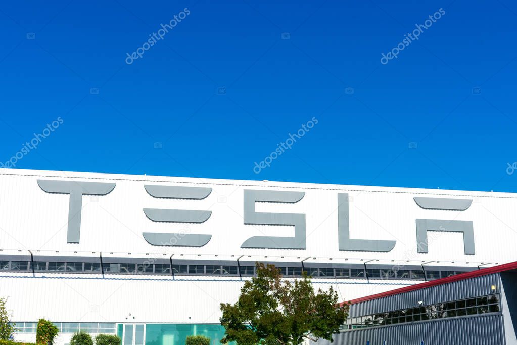 Large Tesla logo displayed on the exterior wall of Tesla Factory, automobile manufacturing plant in Silicon Valley - Fremont, CA, USA - 2019