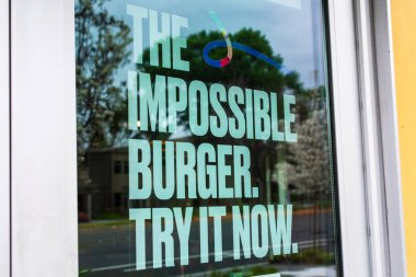 Impossible Burger poster advertises meatless plant-based substitute food at fast food restaurant. The vegan burger supplied by Impossible Foods company - San Francisco, California, USA - 2020 clipart
