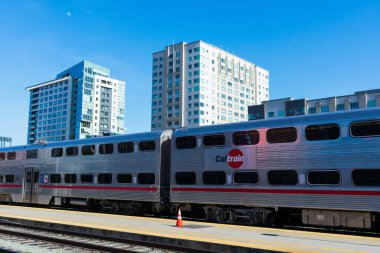 Caltrain İstasyonu 'nun boş yolcu platformunda arka planda modern yerleşim binaları olan iki katlı yolcu vagonu - San Francisco, California, ABD - 2020