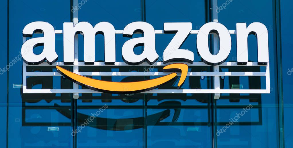 Amazon logo with its signature orange smile reflected in the glass facade of modern company campus - Palo Alto, California, USA - 2019