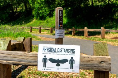 Hindi akbabasıyla fiziksel uzaklık işareti park alanındaki yürüyüş yolunun başında asılıydı - San Jose, California, ABD - Nisan 2020
