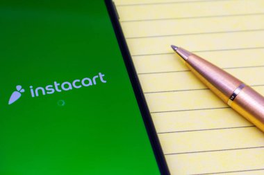 Instacart mobil uygulaması akıllı telefondan açılıyor. Sipariş notları için not defteri yazıyorum. Altın tükenmez kalem - San Jose, CA, ABD - 2020