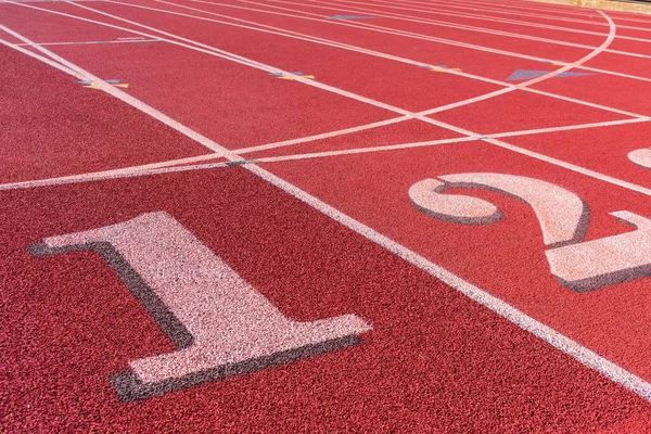 Track and field race course starting line with numbers 1 and 2.