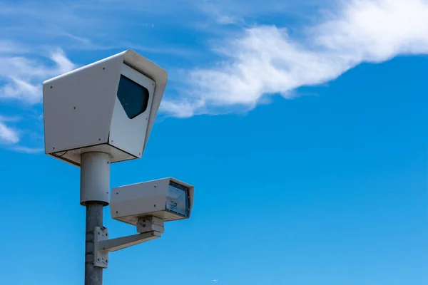 Red light camera. Close up. Traffic enforcement camera. Background blue sky with light clouds during day time.