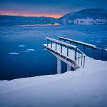 Vinterlandskap med sjö och snötäckt brygga