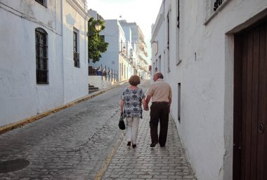 Yaşlı çift el ele tutuşup sokakta yürüyor. 