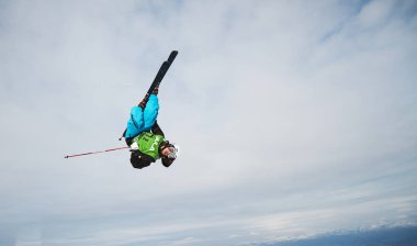 Bulutlu gökyüzü arkaplanına karşı gelen kayakçı 