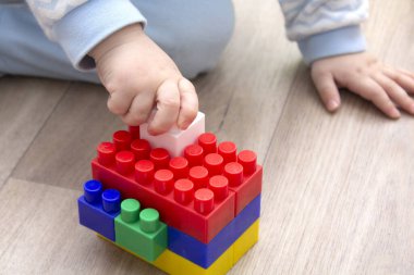 Renkli plastik tuğlalarla oynayan çocukların el resimleri. Çocuk eğleniyor ve parlak inşaat tuğlalarından inşa ediyor. Erken öğrenme. Eğitici oyuncaklar