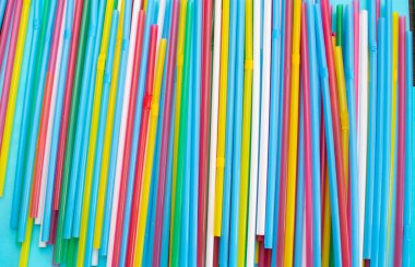 Mavi arka plandaki bir parti için pipet içmek. Yaz kokteylleri için renkli plastik boruların en üst görüntüsü.