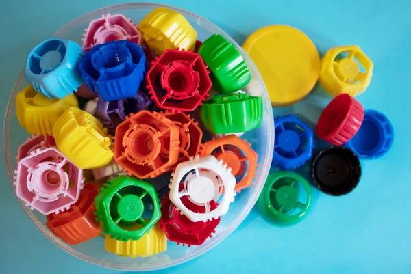 Colored plastic bottle caps on a blue background, top view, disposable plastic