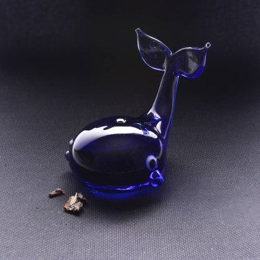 Lumentte camdan yapılmış harika bir mavi balina figürü. Siyah arka planda oyuncak. Önden manzara..