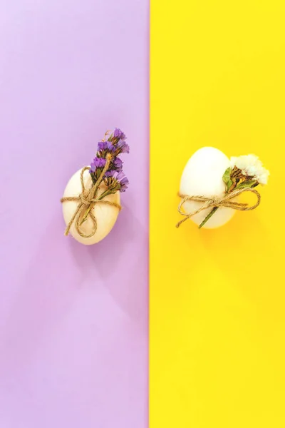 Біле пасхальне яйце на бузковому і жовтому тлі з квітами — стокове фото