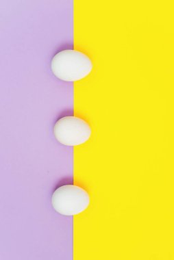 Leylak rengi ve sarı arka planda beyaz paskalya yumurtası