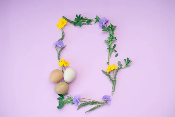 Рамка для тексту з бузкових і жовтих квітів, яєць і зеленого листя на білому тлі. Великодні вітання . — стокове фото