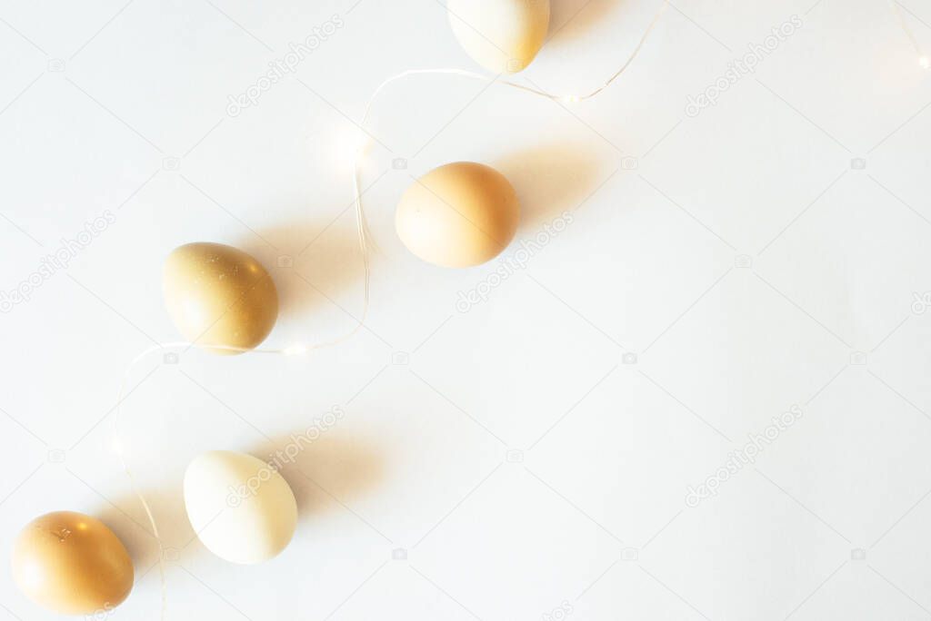 Stylish Easter festive eggs in natural color on a light background with garlands.