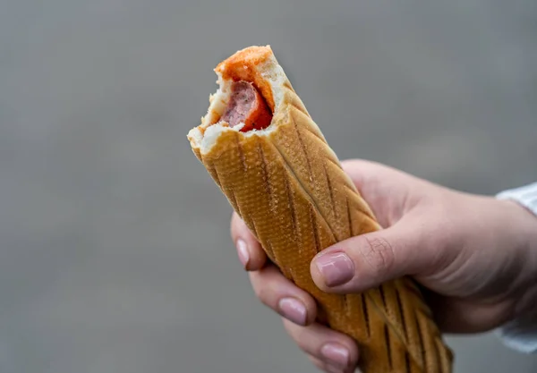 Γυναίκα χέρι κρατώντας ένα δάγκωμα γαλλικό hot dog fast food — Φωτογραφία Αρχείου
