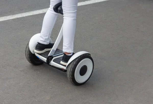 Chica montando un giroboard eléctrico blanco en una calle — Foto de Stock