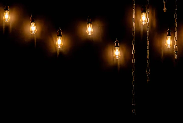 Lâmpadas de incandescência quentes com correntes de metal em um fundo de parede Fotografia De Stock