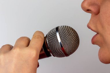 Uzun boylu, mikrofonlu bir kadın karaoke profiliyle şarkı söylüyor.