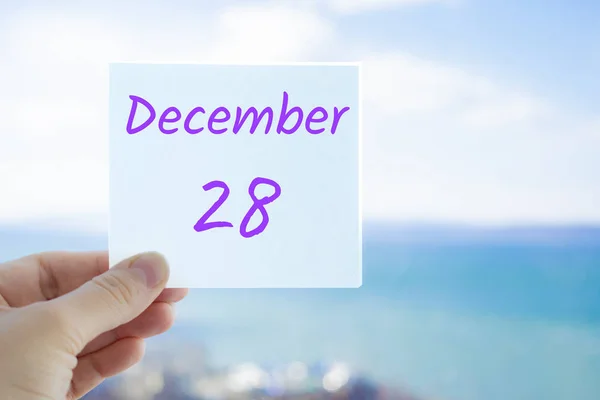 28 de diciembre. Pegatina de mano con texto del 28 de diciembre sobre el fondo borroso del mar y el cielo. Copia espacio para texto. Mes en concepto de calendario — Foto de Stock