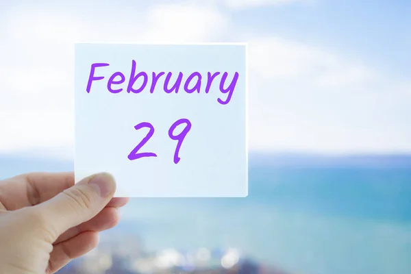 29 de febrero, último día del invierno. Pegatina de mano con texto del 29 de febrero sobre el fondo borroso del mar y el cielo. Copia espacio para texto. Mes en concepto de calendario — Foto de Stock