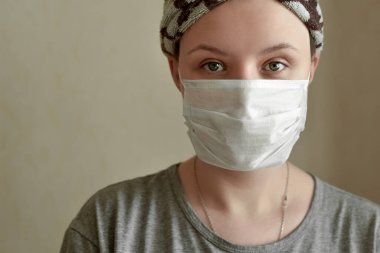 Sarıklı ve koruyucu maskeli genç bir kadın kameraya bakıyor. Koronavirüsün yayılmasını önlemek için karantina için evde kalın. COVID-2019 'dan korunma kavramı.