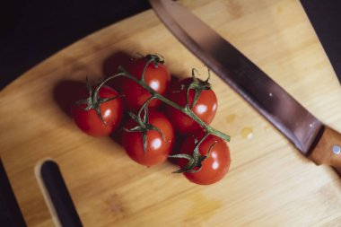Kiraz domatesleri bir sebze bıçağıyla doğrama tahtasının üzerinde yatar. Olgun sebzeler. Domates seti. Siyah arka plan. Sağlıklı beslenme. Vejetaryen yemeği. Sağlıklı beslenme. Ürün tasarımı kavramı. # Sanatı kilitle