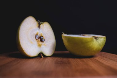 Dilimlenmiş yeşil elma tahta bir tahtanın üzerinde yatıyor. Organik meyve. Sağlıklı bir yaşam tarzı. Tatlı meyve. Vejetaryen sağlıklı yiyecekler. Doğal arka plan. Karanlık arka plan. # Sanatı kilitle