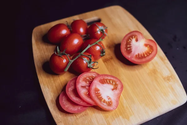 sliced tomatoes and cherry tomatoes are on the cutting Board. Ripe vegetables. Tomato set. Dark background. Healthy diet. Vegetarian food. Healthy diet. The design concept of the product. #LockdownArt