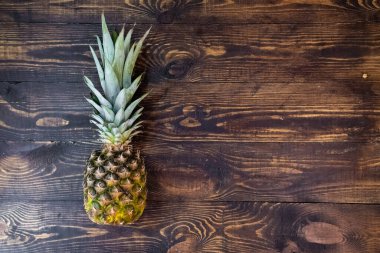 Ananas ahşap bir masanın üzerinde yatıyor. Yukarıdan bak. Vejetaryen sağlıklı yiyecekler. Tatlı meyve. Organik meyve. Sarı ananasın yakın çekimi