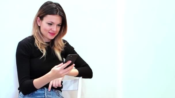흰색 배경에 있는 매력적 인 여성 이 핸드폰을 보고 타자를 치는 모습 — 비디오
