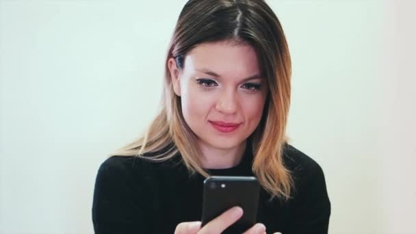 Atractiva hembra sobre fondo blanco mira su teléfono y emocionado por una gran cantidad de gustos en una red social — Vídeo de stock