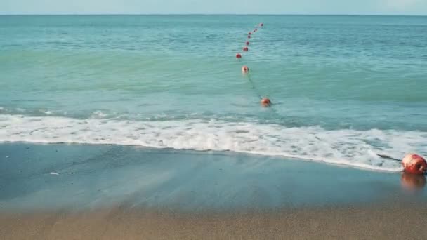 Pohled na letní písečnou pláž s protijedoucími mořskými vlnami a červenými bójemi — Stock video