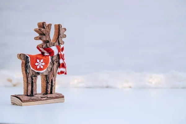 Fondo de Navidad con estatuilla de ciervo de madera sobre un fondo blanco de nieve y luces —  Fotos de Stock