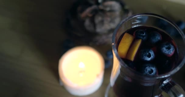 Irish coffee glass with mulled wine burning candle, blueberries, wood background — Stock Video