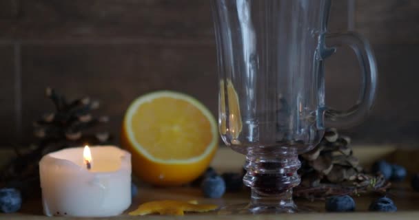 Hot mulled wine is poured into a Irish coffee glass on a wood background. — Stock Video