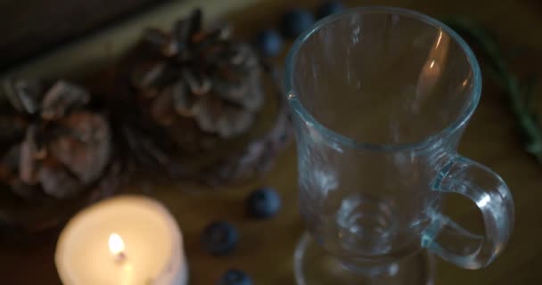 Hot mulled wine is poured into a Irish coffee glass on a wood background. — Stock Video