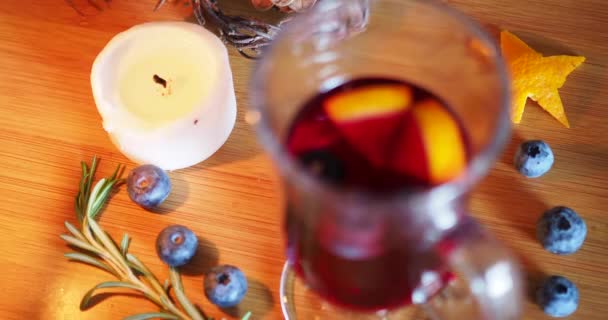Rozsvíceno, světlo svíčky v blízkosti horkého svařeného vína na dřevěném pozadí. — Stock video