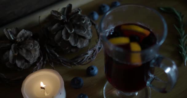 Luz acesa, acenda a vela perto do vinho quente quente em um fundo de madeira . — Vídeo de Stock