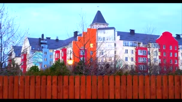 View of a modern multi-colored apartment building behind a yellow fence — 비디오