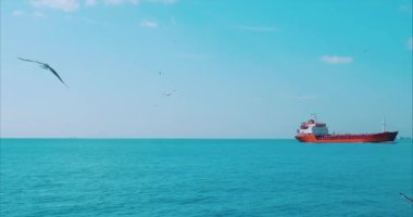 Büyük kırmızı tanker yazın sağ tarafındaki mavi denizde yol alıyor.