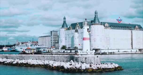 Полет вокруг современного белого и красного маяка в гавани Стамбула с летающими чайками. Средиземное море спокойные волны многие бетонные буи причал волнолом судоходства порт городской пейзаж — стоковое видео